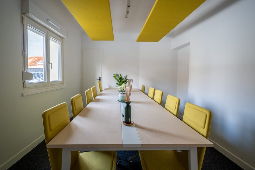 Salle de réunion avec chaises jaunes et plafond acoustique